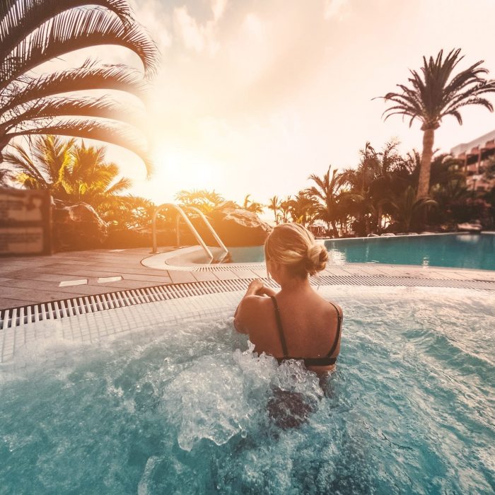 YYoung influencer woman relaxing inside jacuzzi at sunset outdoor